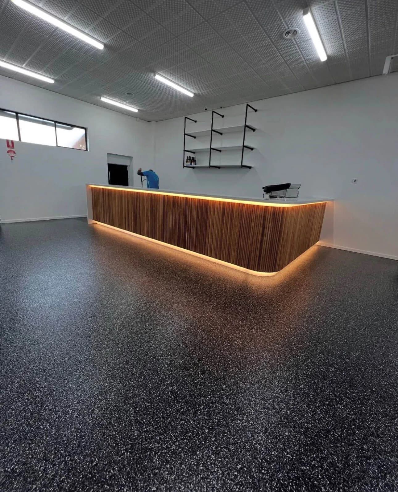 Dark flake epoxy floor around an illuminated timber reception counter