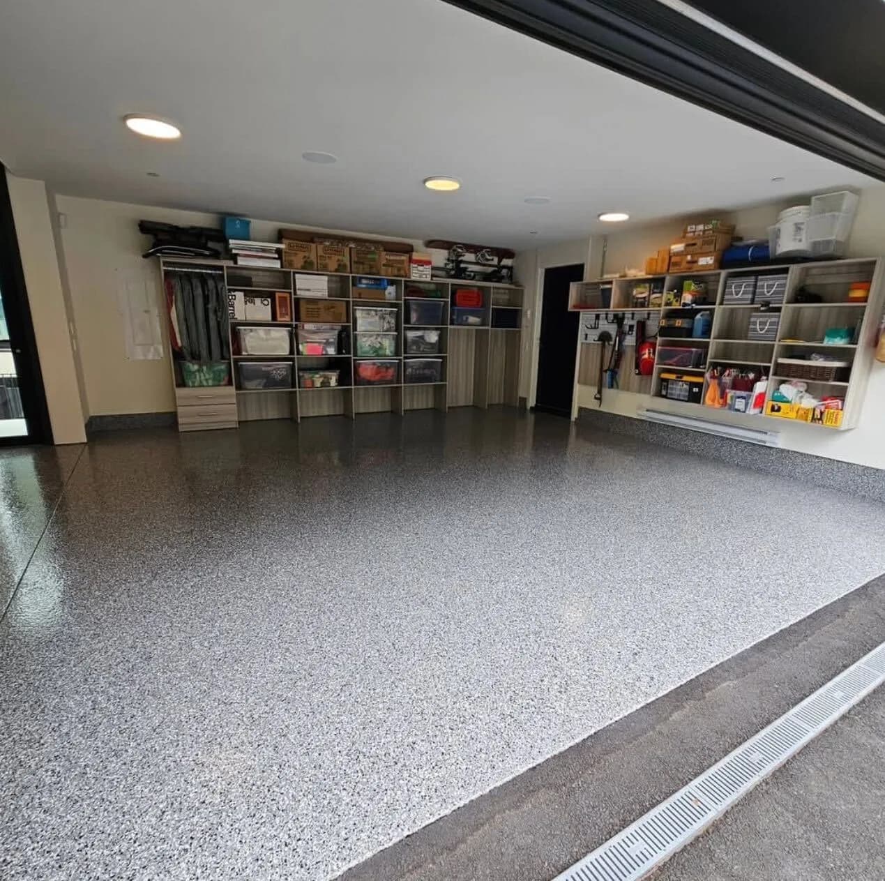 Grey flake epoxy garage floor with coordinated coated wall edges and storage cabinets