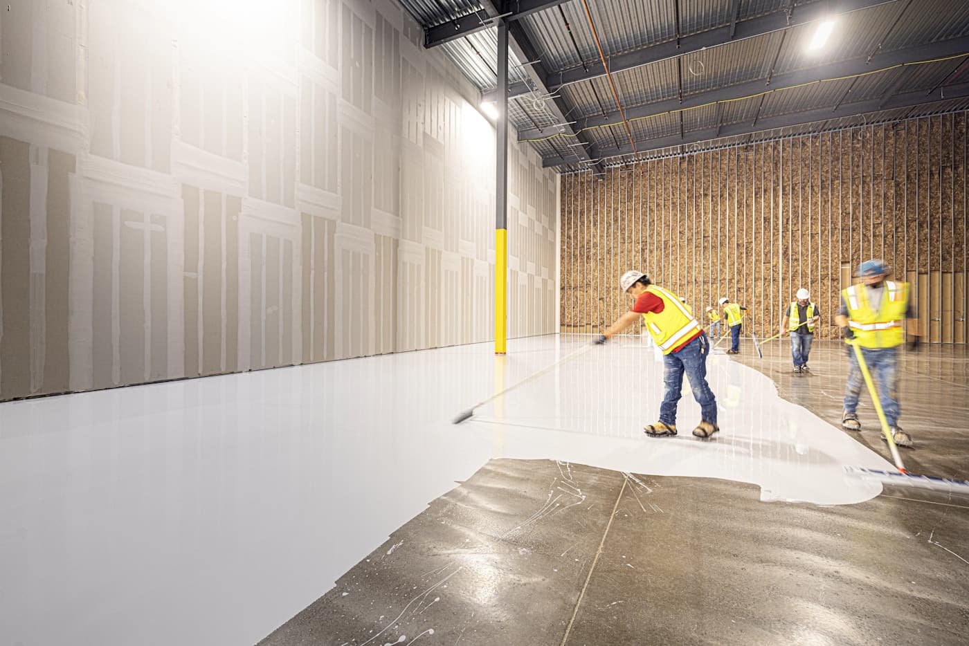 Crew applying a coating to a prepared commercial concrete floor